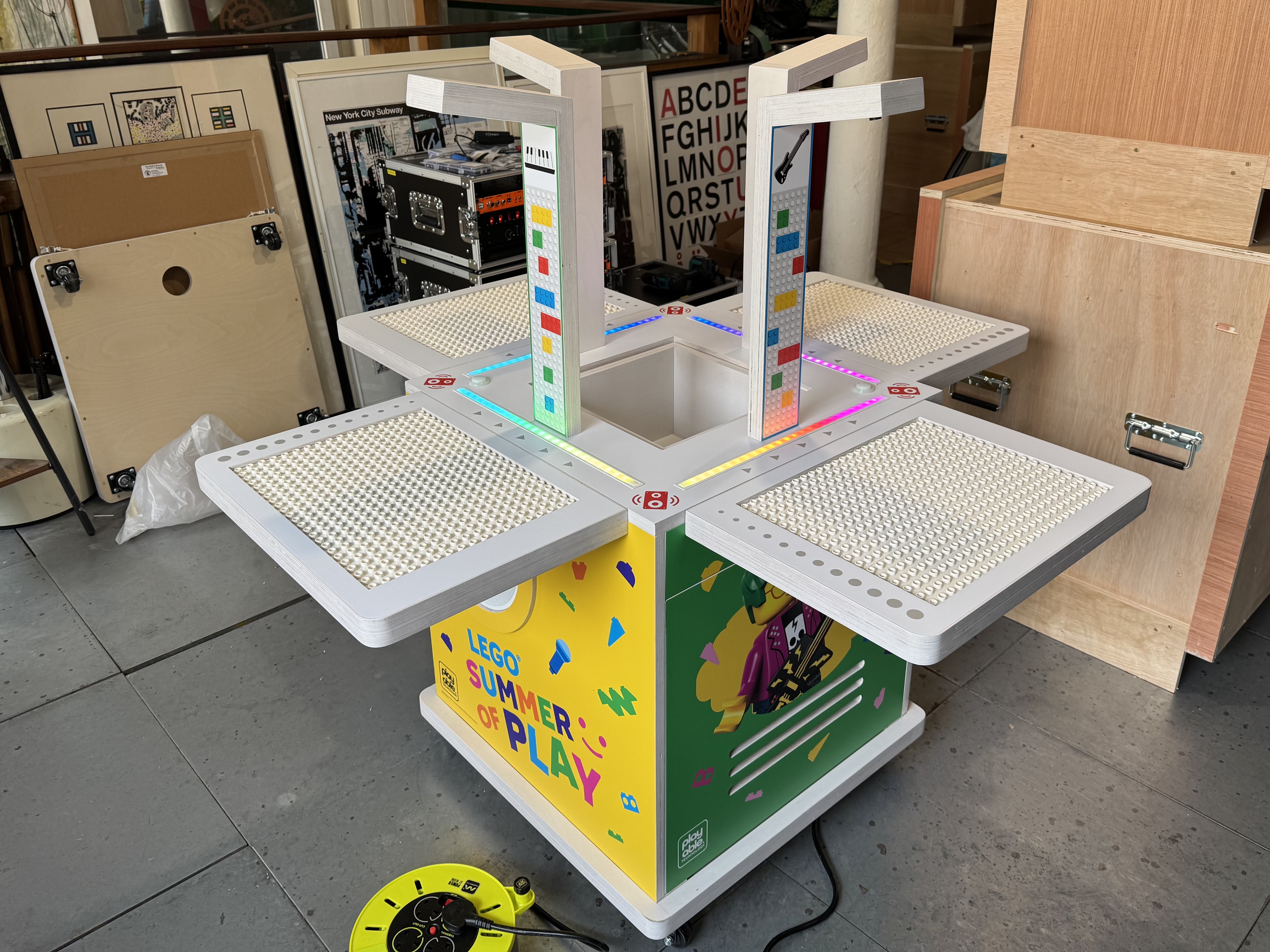 A BeatBricks unit powered up in its LEGO Summer of Play livery, four white baseplates around two lit camera columns, built in the Playable workshop.