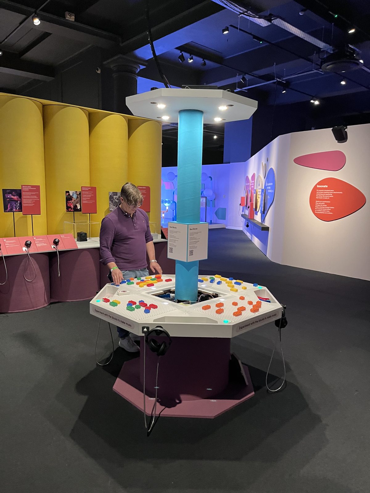 Playable co-founder Ben Schögler arranges coloured DUPLO bricks on the octagonal Music Maker table, beneath the camera column, at the Turn It Up exhibition.