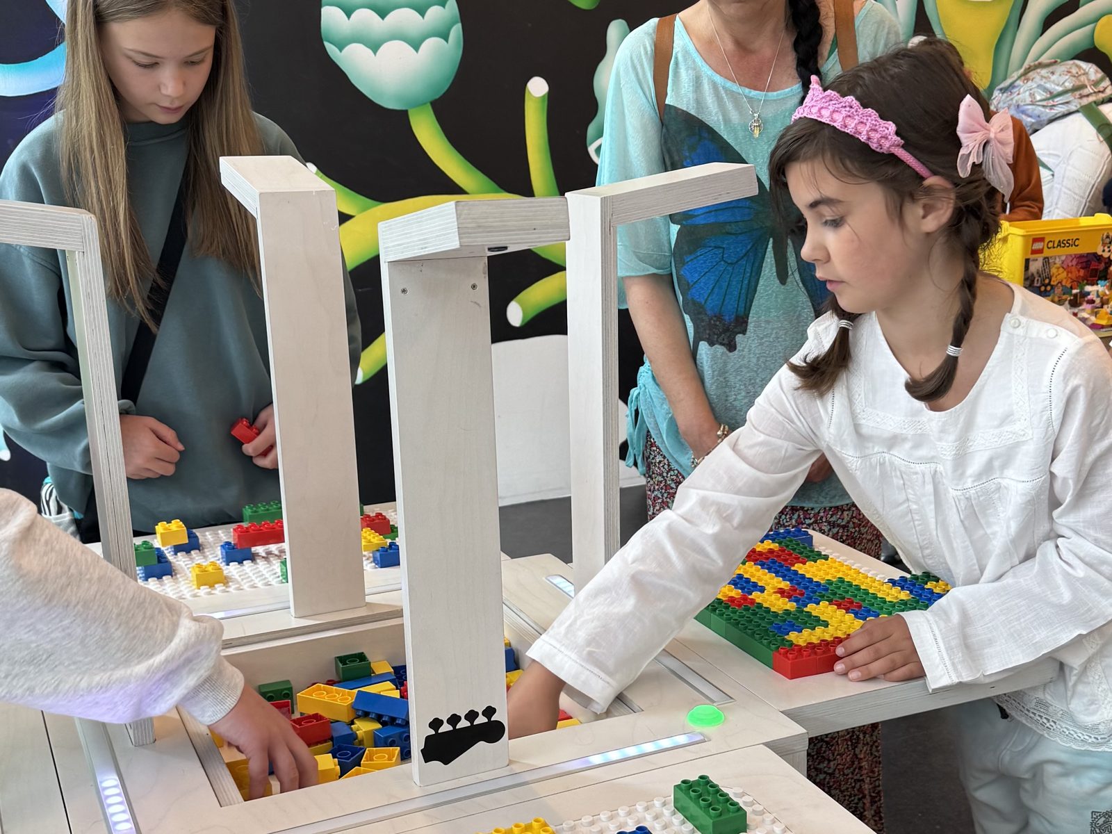 Children play BeatBlocks Live together in V&A Dundee's Robertson Studio, a colourful mural behind them.