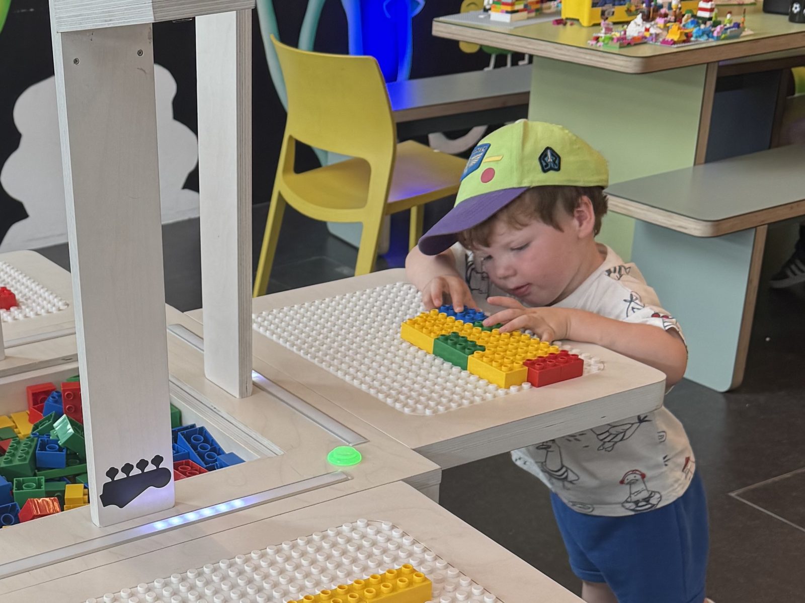 A young boy carefully places a row of coloured bricks on a BeatBlocks Live baseplate at V&A Dundee.