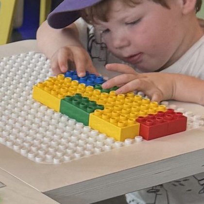 A child places a row of yellow, green, red and blue bricks on the BeatBlocks Live baseplate.