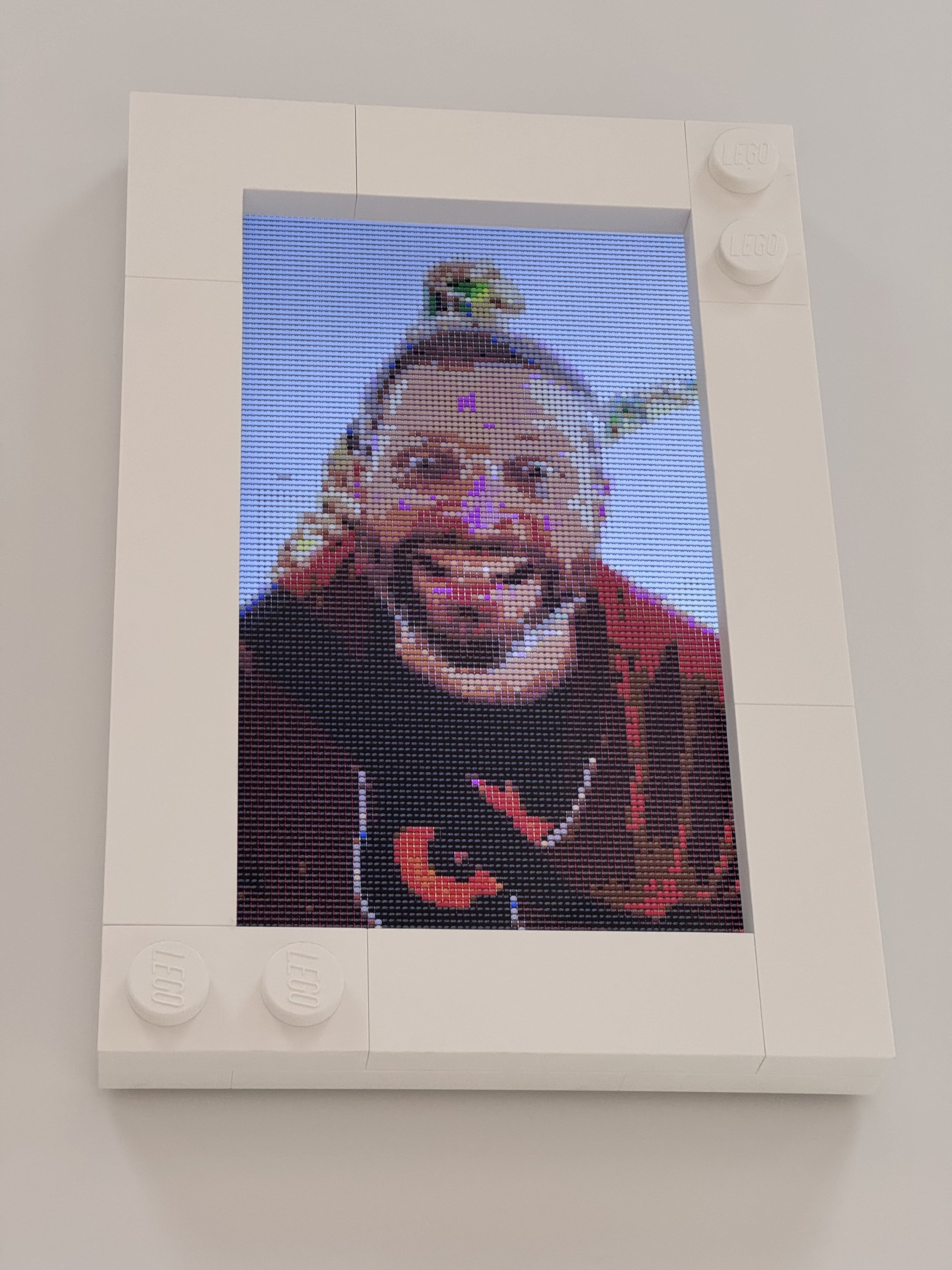 A LEGO House interactive exhibit showing a LEGO-style pixelated portrait of Playable CTO David Skulina, a dinosaur behind.