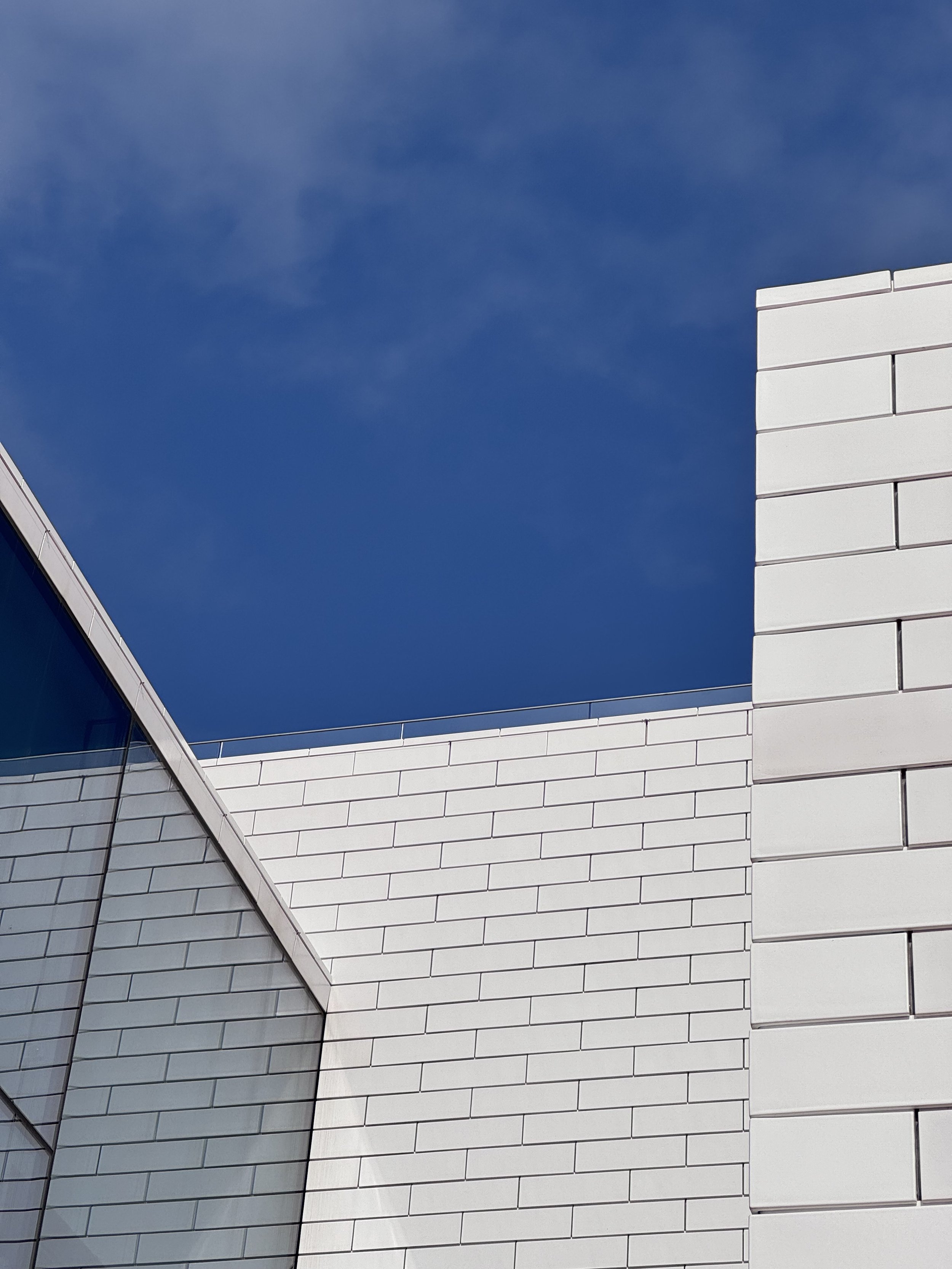 An architectural view of the LEGO House from an upper terrace: white cladding that looks built from LEGO, against a deep blue sky.